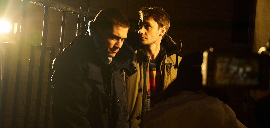 Two TV crew members calmly discussing a disagreement backstage